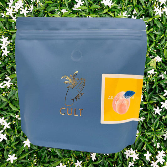 Blue packaging with 'CULT' branding on a green leafy background