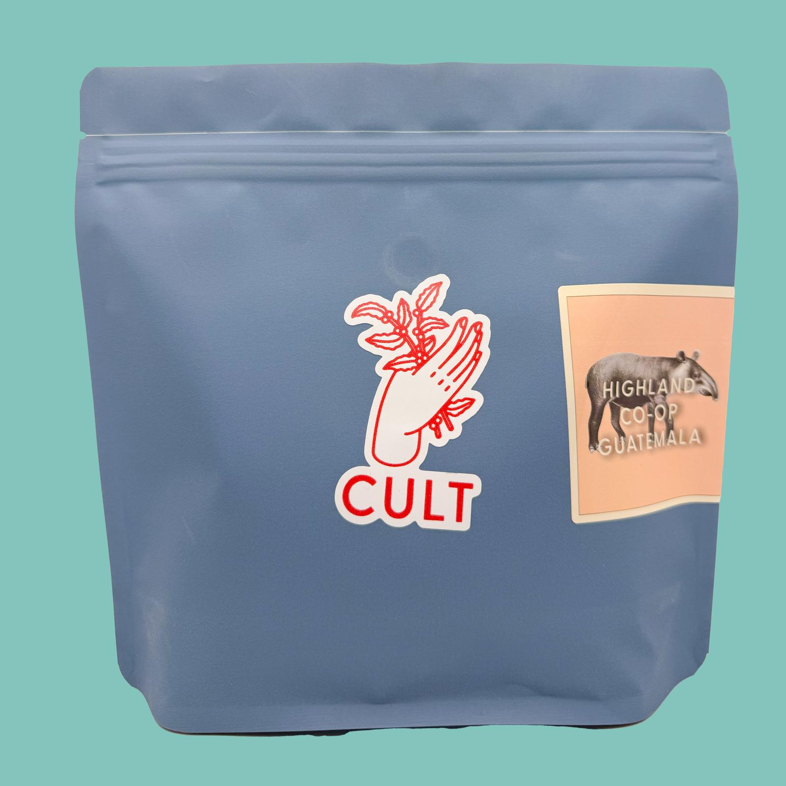 Blue coffee bag with 'Cult' branding and a label on a teal background, Highland Co-op Guatemala