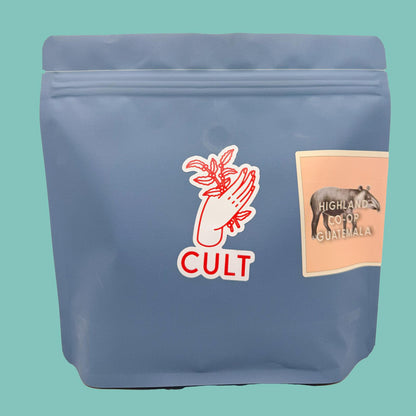 Blue coffee bag with 'Cult' branding and a label on a teal background, Highland Co-op Guatemala