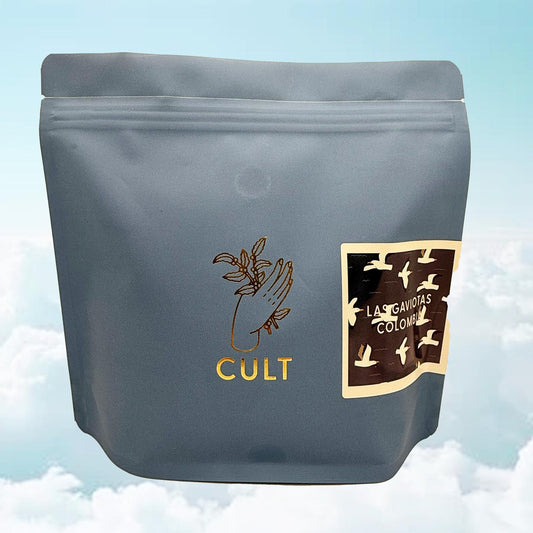 Gray coffee packaging with 'Cult' branding and'Las Gaviotas Colombia'  on a light blue background. 